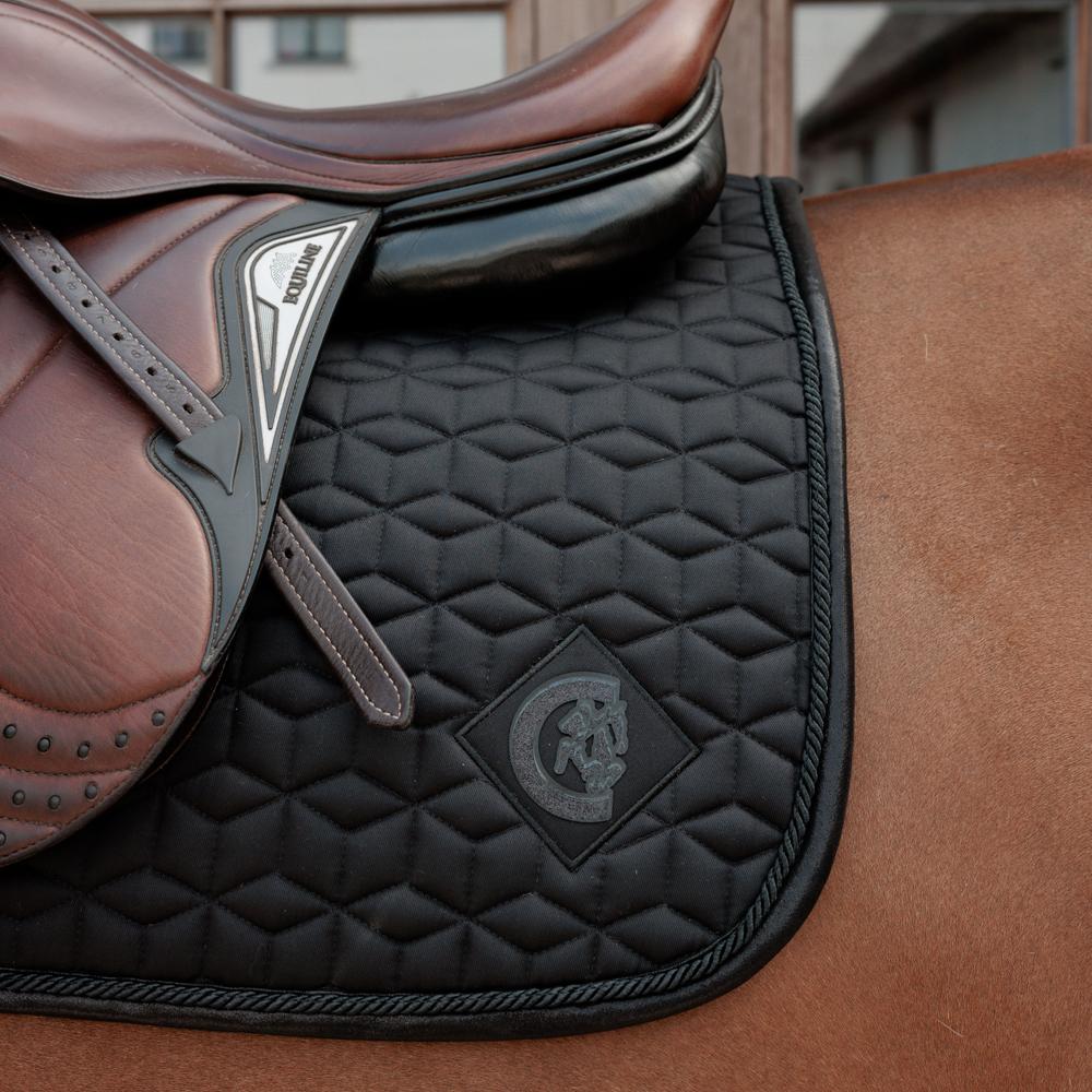 Black saddlepad under a brown saddle on a bay horse