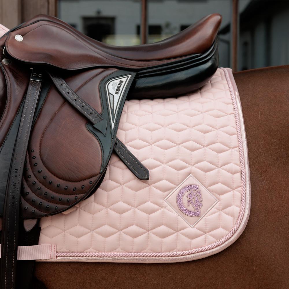 Pink saddlepad under a brown saddle on a bay horse