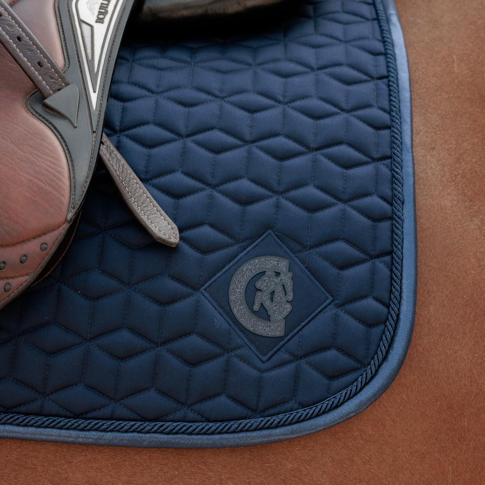 Navy saddlepad under a brown saddle on a bay horse