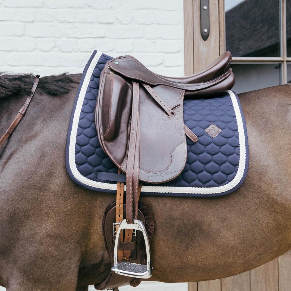 Navy saddlepad under a brown saddle on a bay horse
