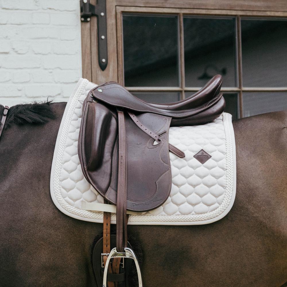 Beige saddlepad under a brown saddle on a bay horse