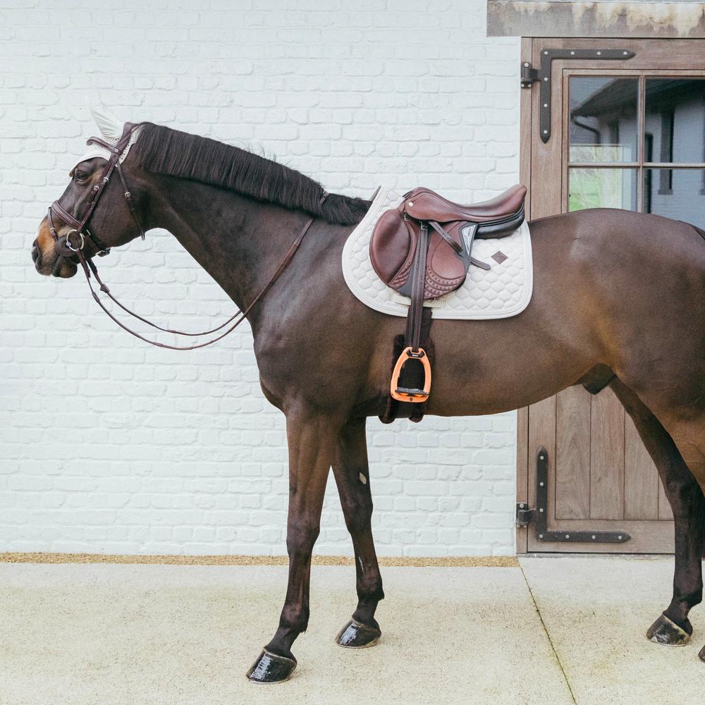Beige saddlepad under a brown saddle on a bay horse