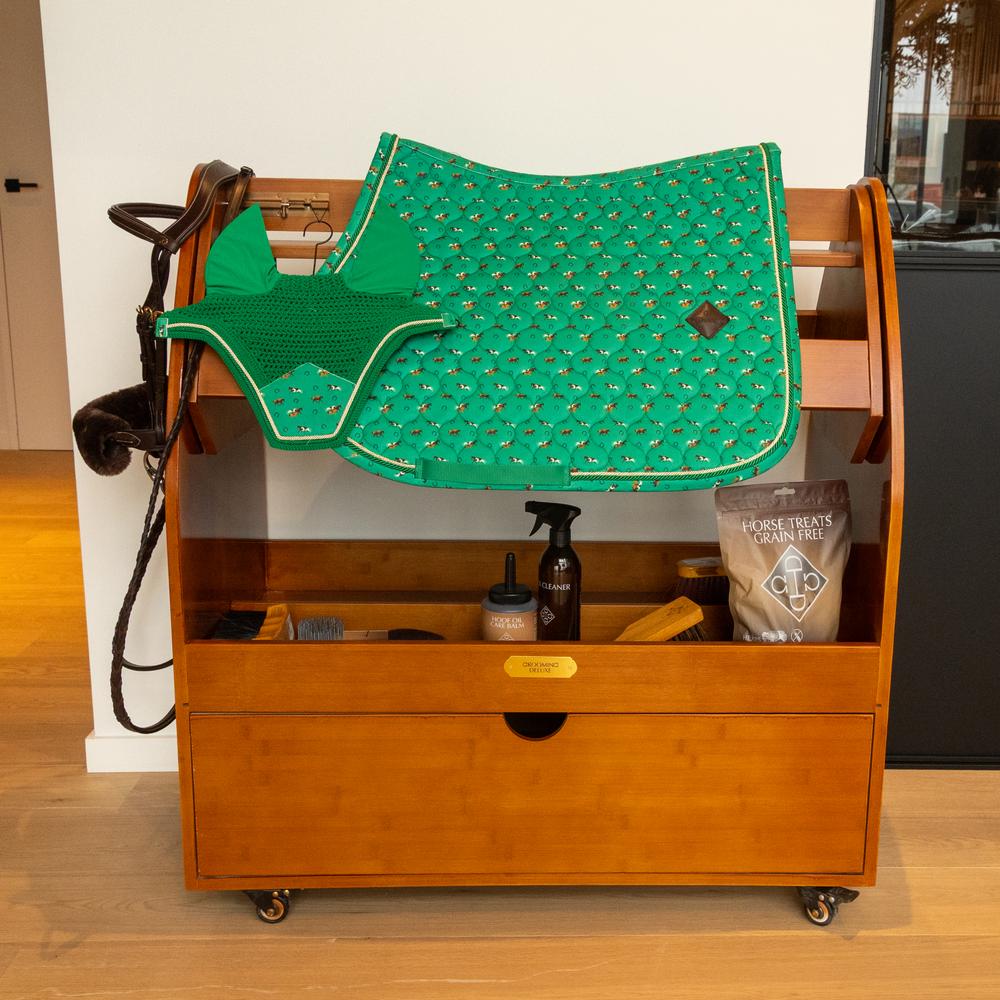 Green horse themed saddlepad and ears on a wooden saddle stand