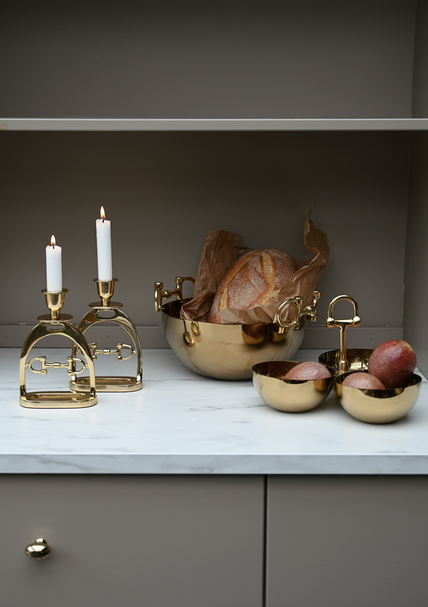 Decorative items including gold candle holders and bowls on a marble surface with a neutral background.