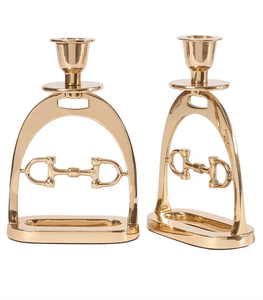 Two gold candle holders shaped like horse stirrups on a white background