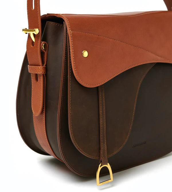 Equestrian saddle shaped handbag on a white background