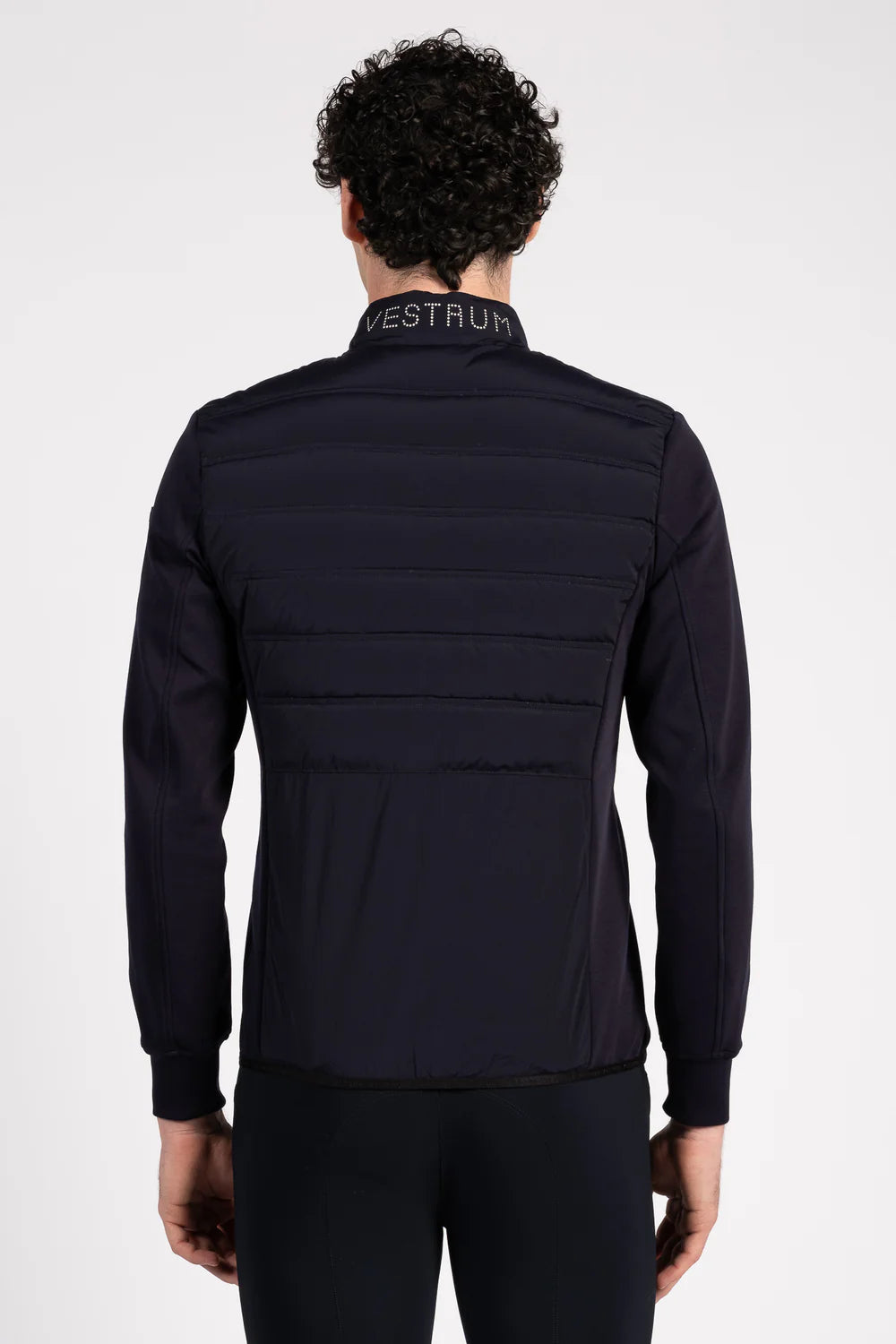 Person wearing a black jacket with 'Vestrum' branding on a white background