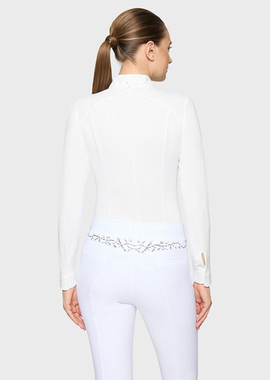 A woman shown from the back wearing a white long-sleeve mock-neck top and white fitted pants with a decorative embroidered waistband.