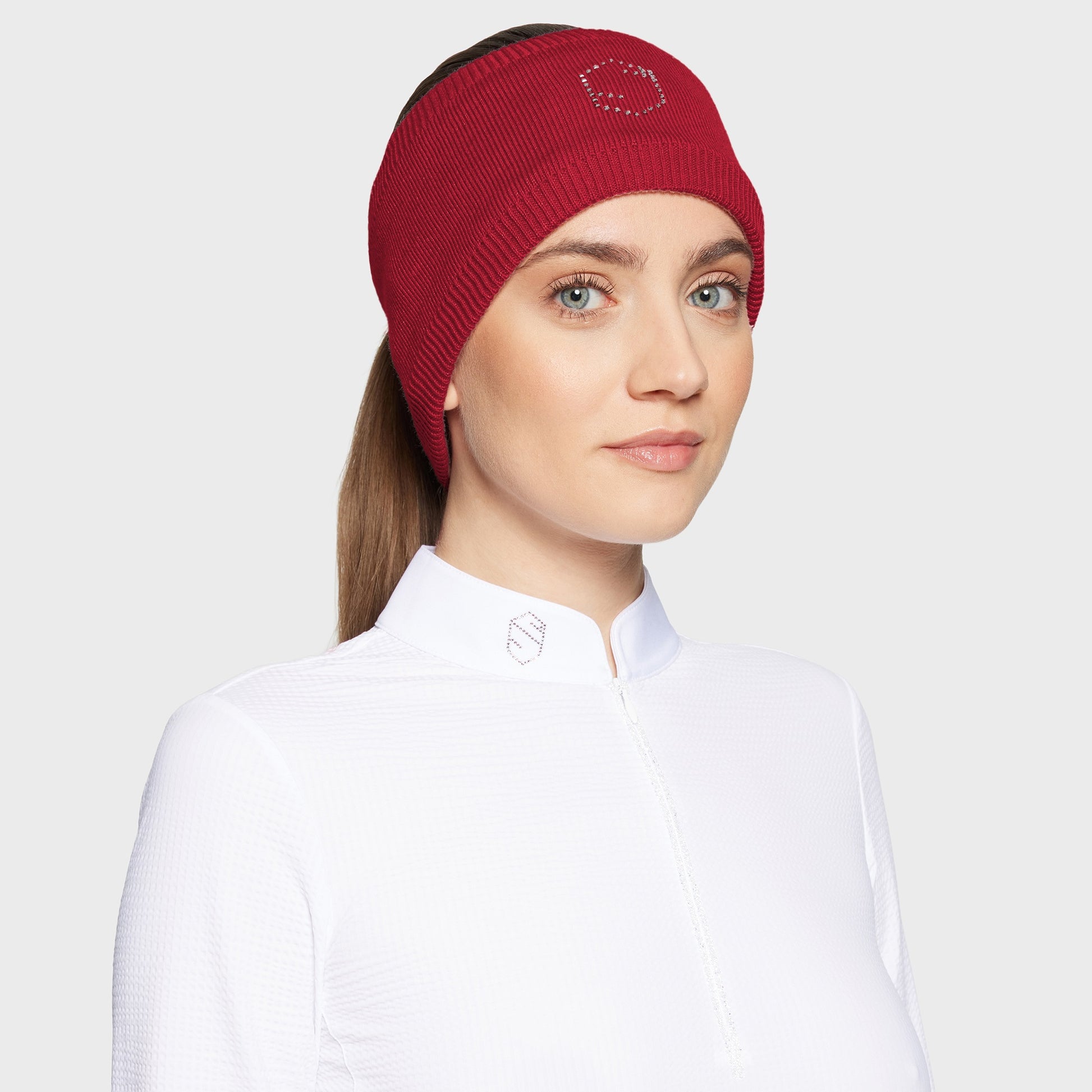 Woman wearing a red knit headband with a logo on a white background