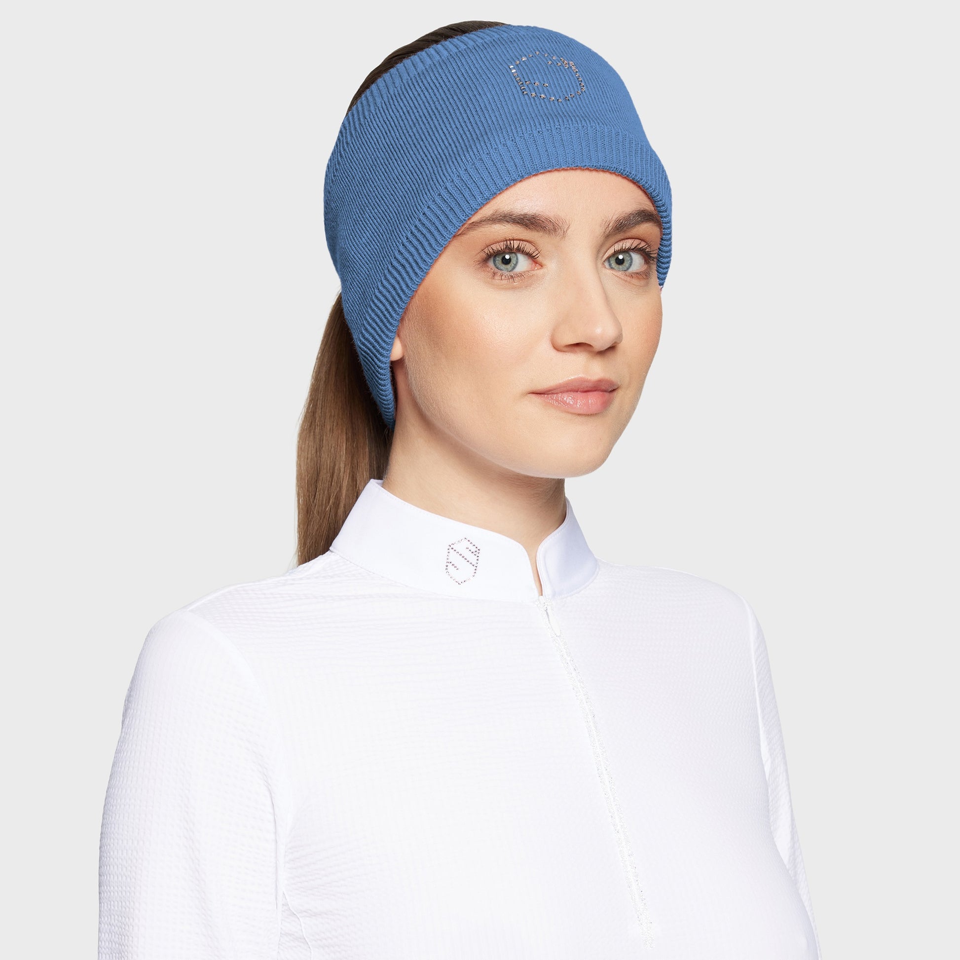 Woman wearing a blue headband with a glitzy logo and a white shirt on a white background