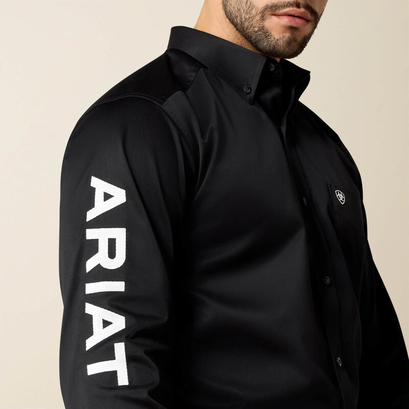 Black shirt with 'ARIAT' branding on a beige background