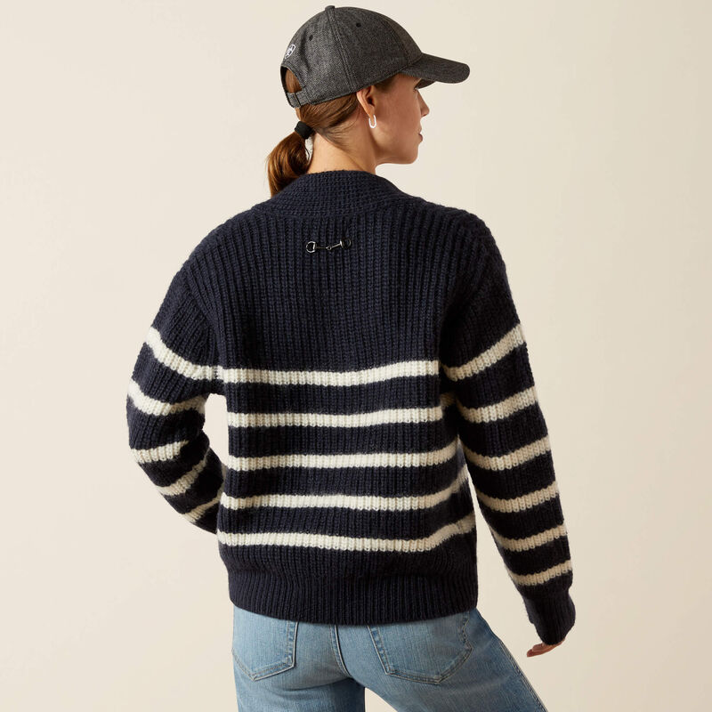 Person wearing a navy and white striped sweater with a cap on a beige background