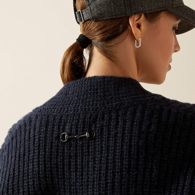 Person wearing a dark blue knitted sweater with a beige background