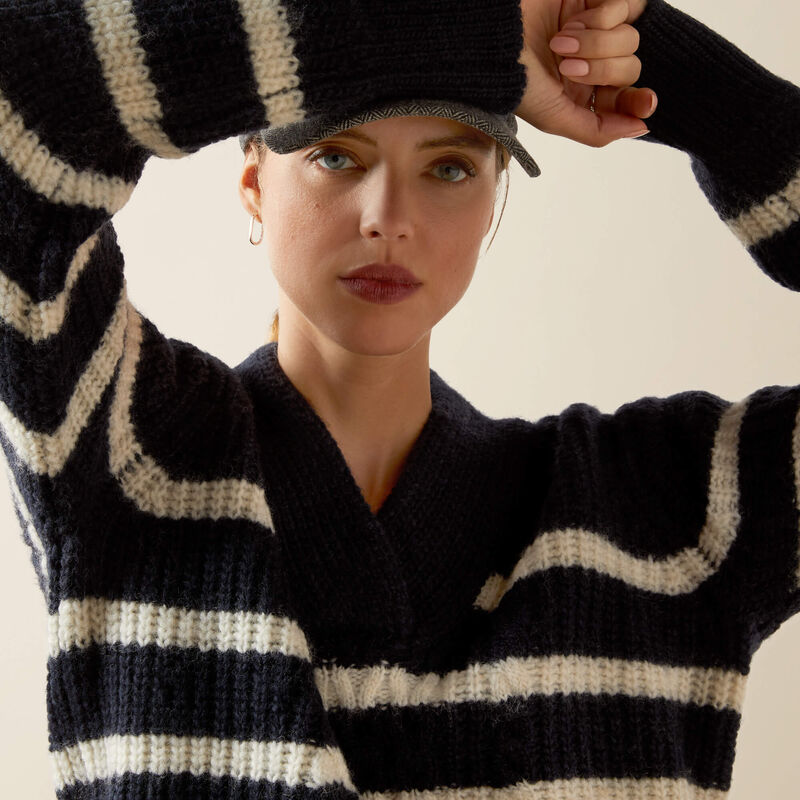 Person wearing a navy and white striped sweater with a neutral background