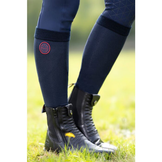 Person wearing a pair of navy socks with a red badge on a grass background