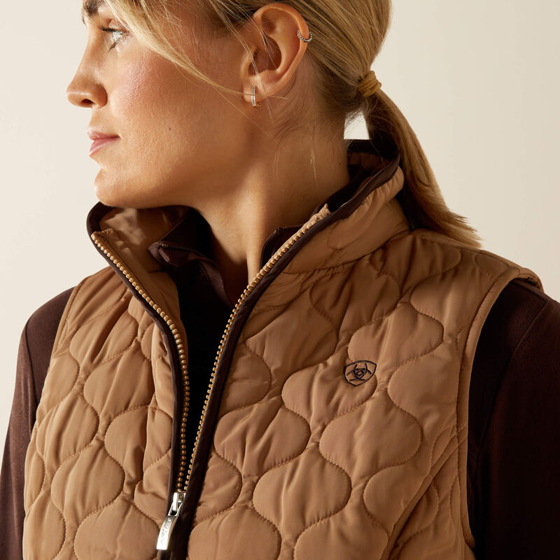 Person wearing a beige quilted vest on a beige background