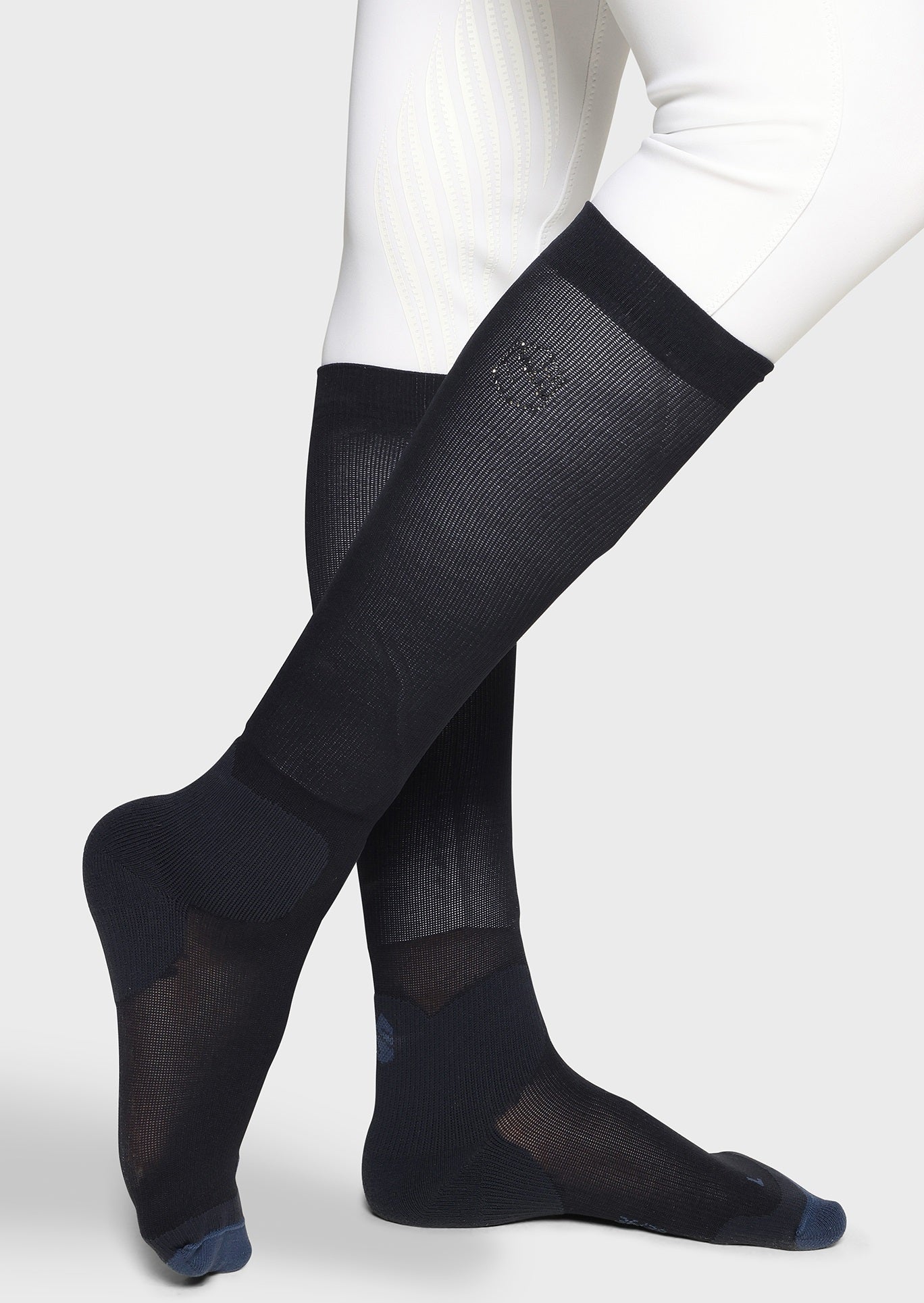 Black knee-high socks worn with white pants on a light gray background