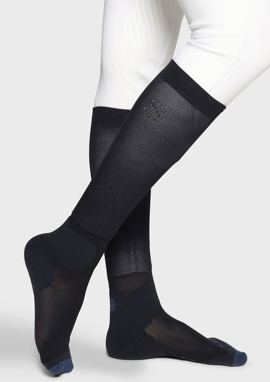 Black knee-high socks worn with white pants on a light gray background