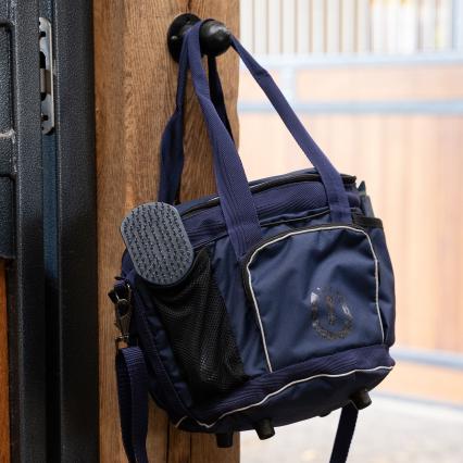 Navy blue bag with a textured pouch attached, hanging on a wooden surface.