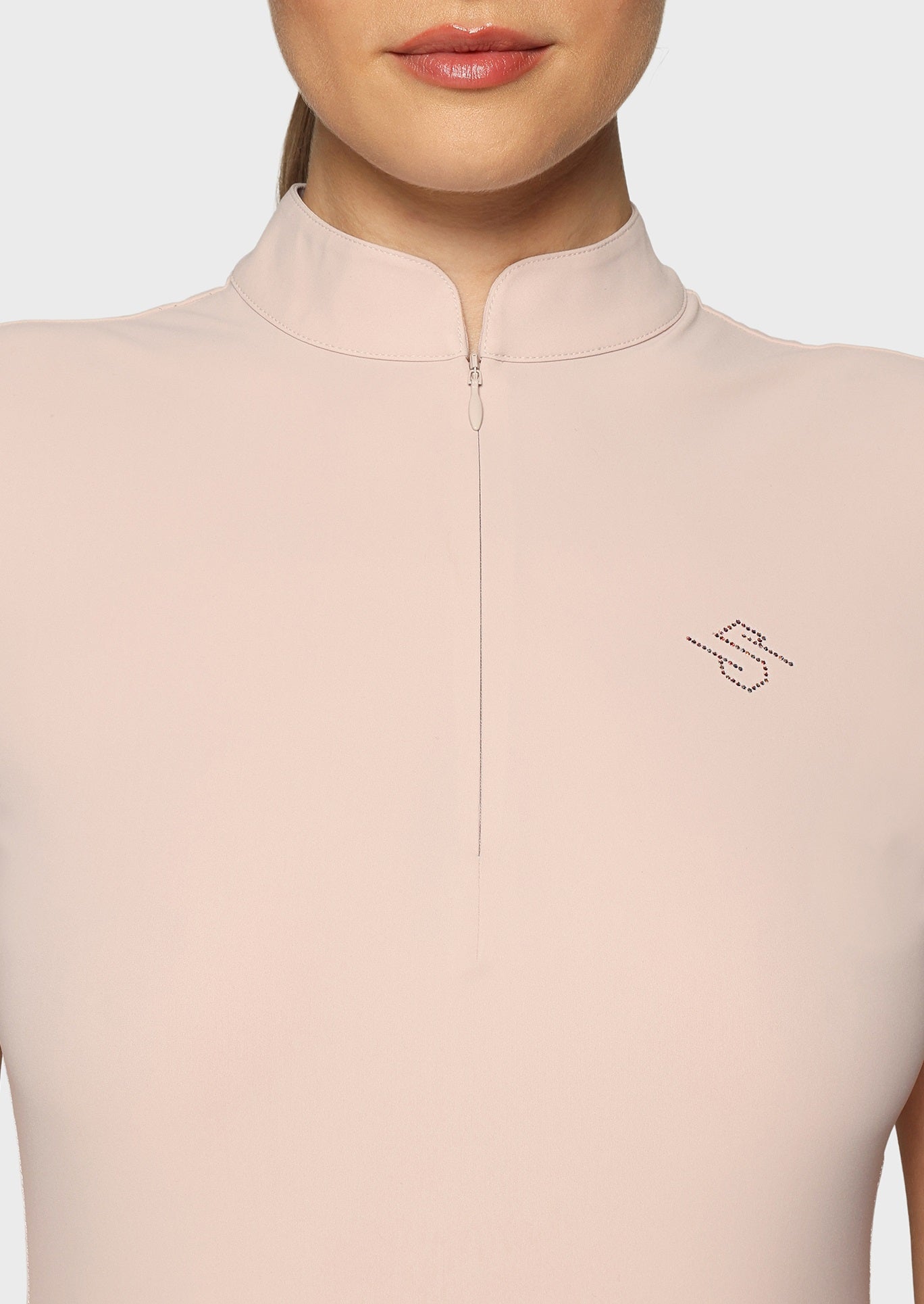 Close up of a woman wearing a pink shirt on a beige background