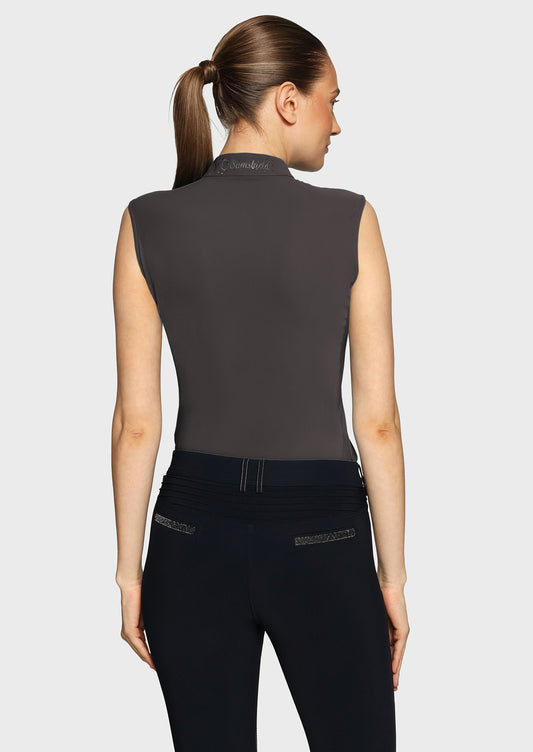 Woman wearing a grey sleeveless top and black breeches on a beige background