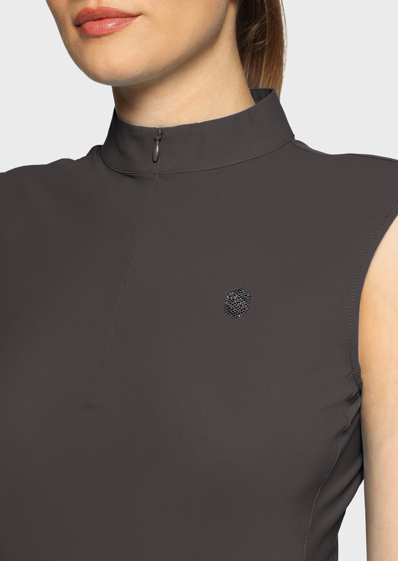 Woman wearing a grey sleeveless top  on a beige background