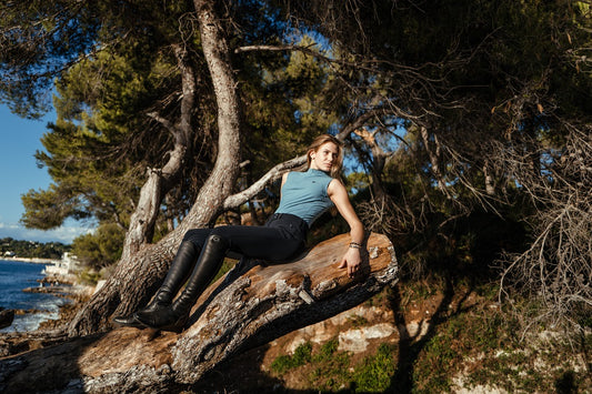 Woman leaning against a tree trunk in a beach setting
