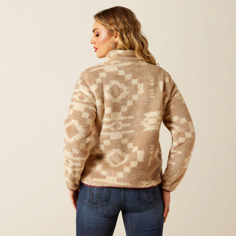 Woman wearing a patterned beige fleece jacket on a plain background