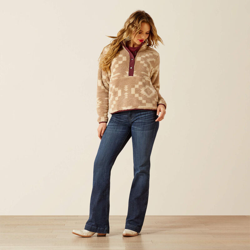 Woman wearing a patterned sweater and blue jeans on a plain background