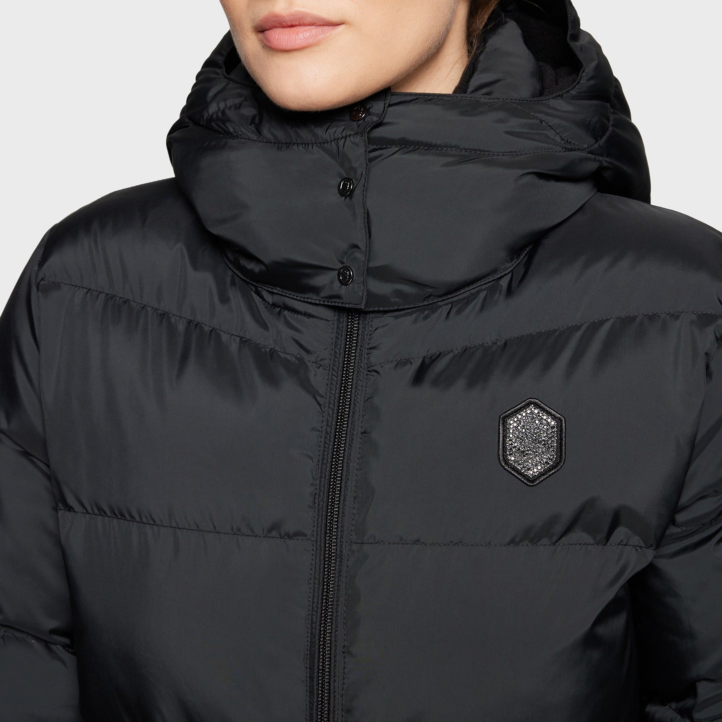 Black puffer jacket with a brand logo on a neutral background