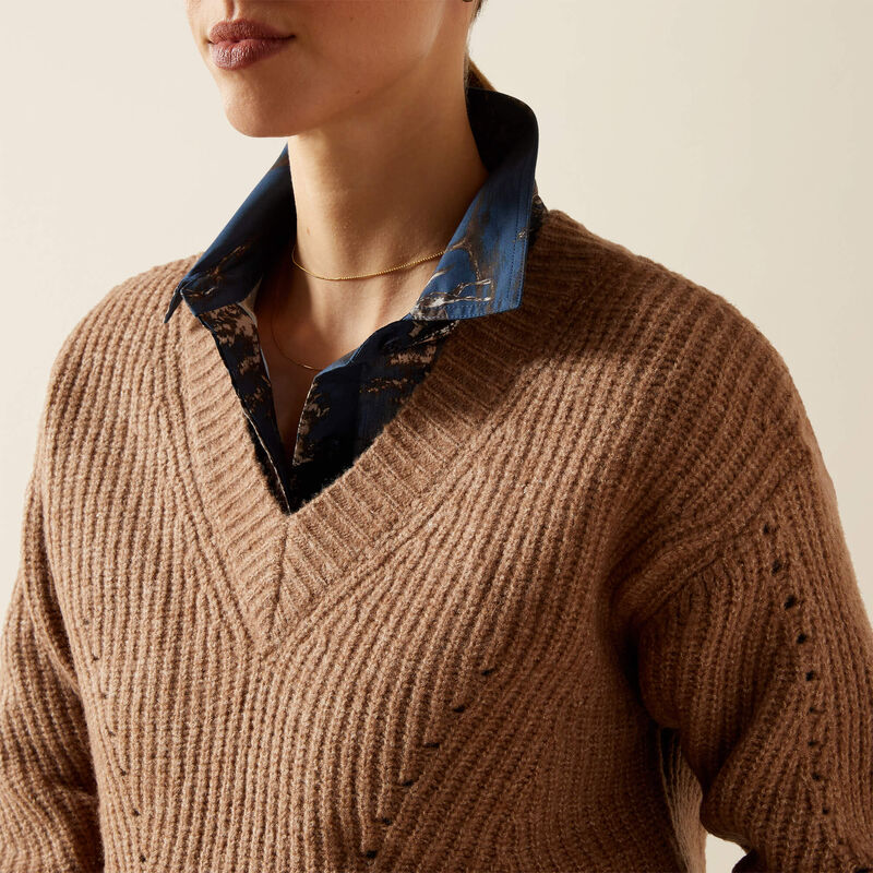 Brown sweater with a blue collar against a neutral background