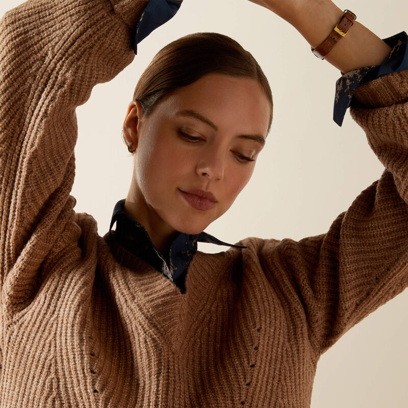 Woman wearing a brown sweater with a plain background