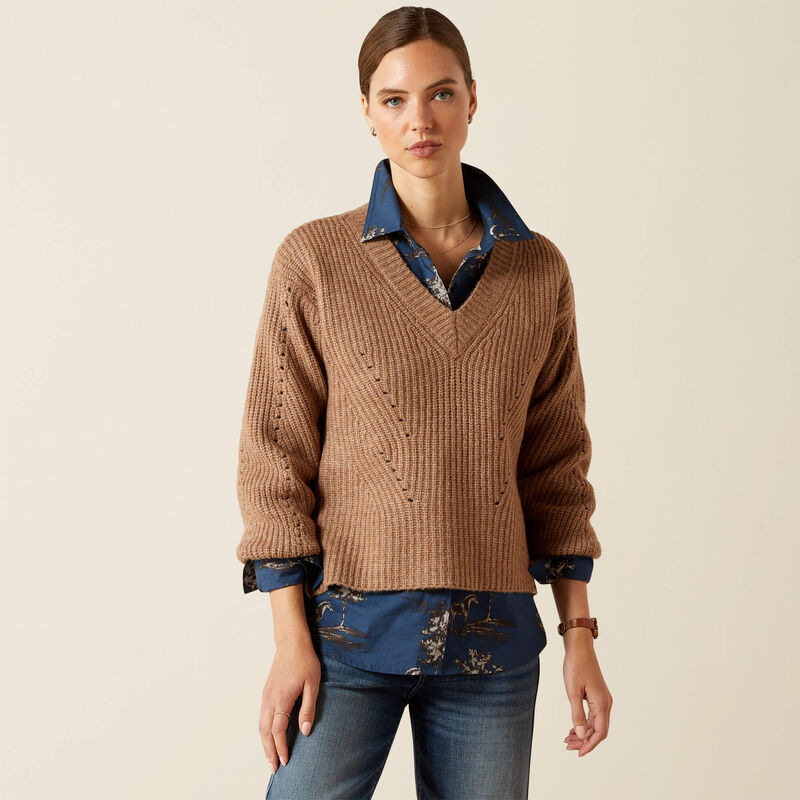 Woman wearing a brown sweater over a blue shirt with a beige background