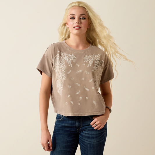 Woman wearing a beige t-shirt with floral patterns on a plain background