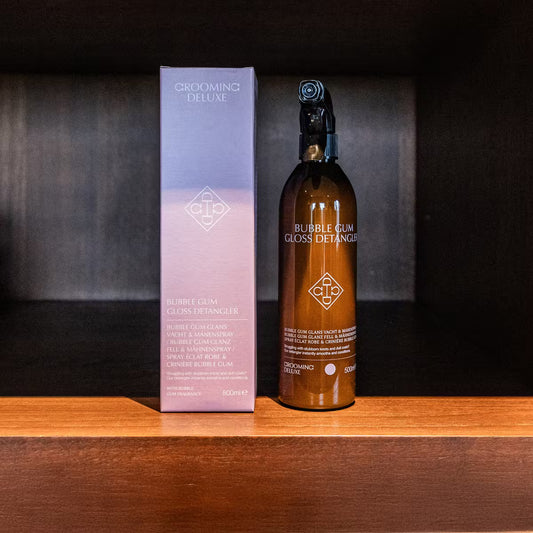 Bottle and packaging of 'Bubble Gum Gloss Detangler' on a wooden shelf with a dark background