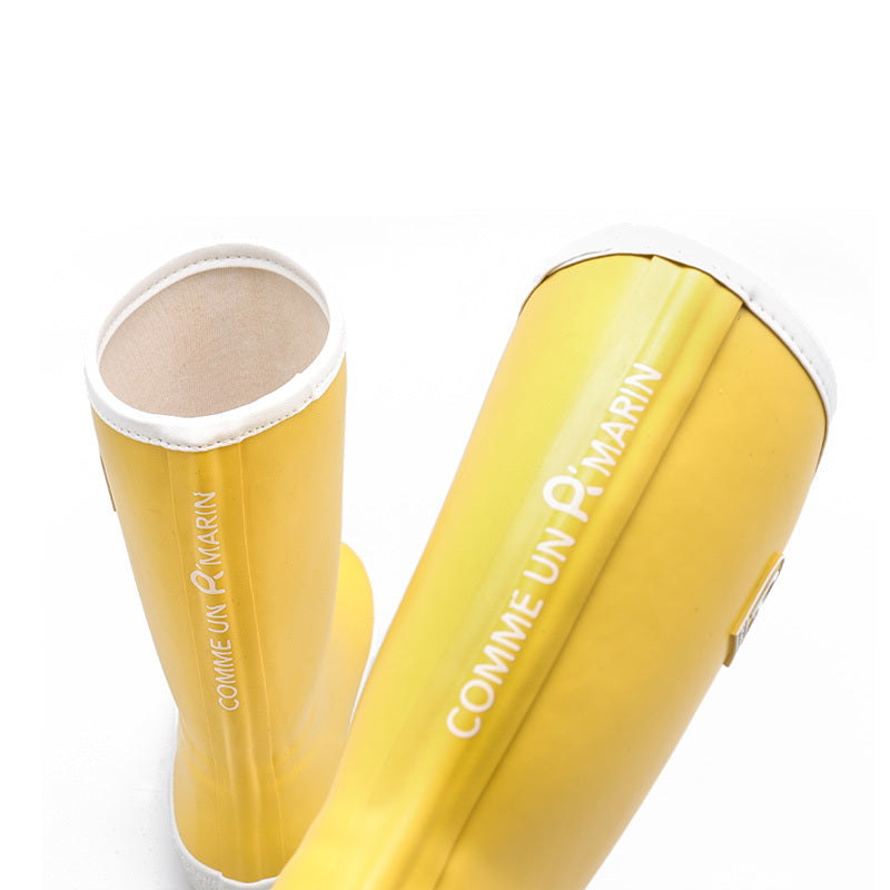 Yellow children's wellies with french writing on a white background