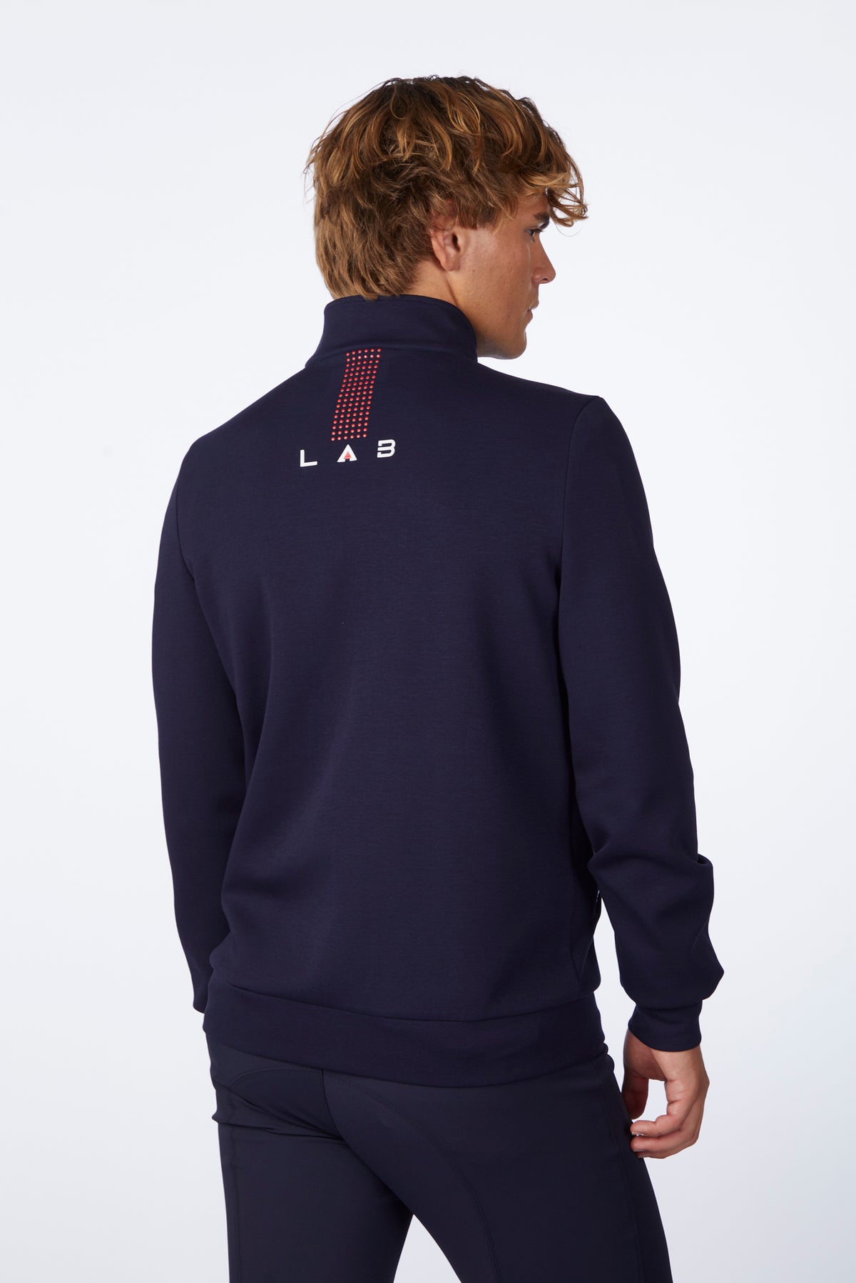 Person wearing a navy blue tracksuit with 'LAB' branding on the back against a white background