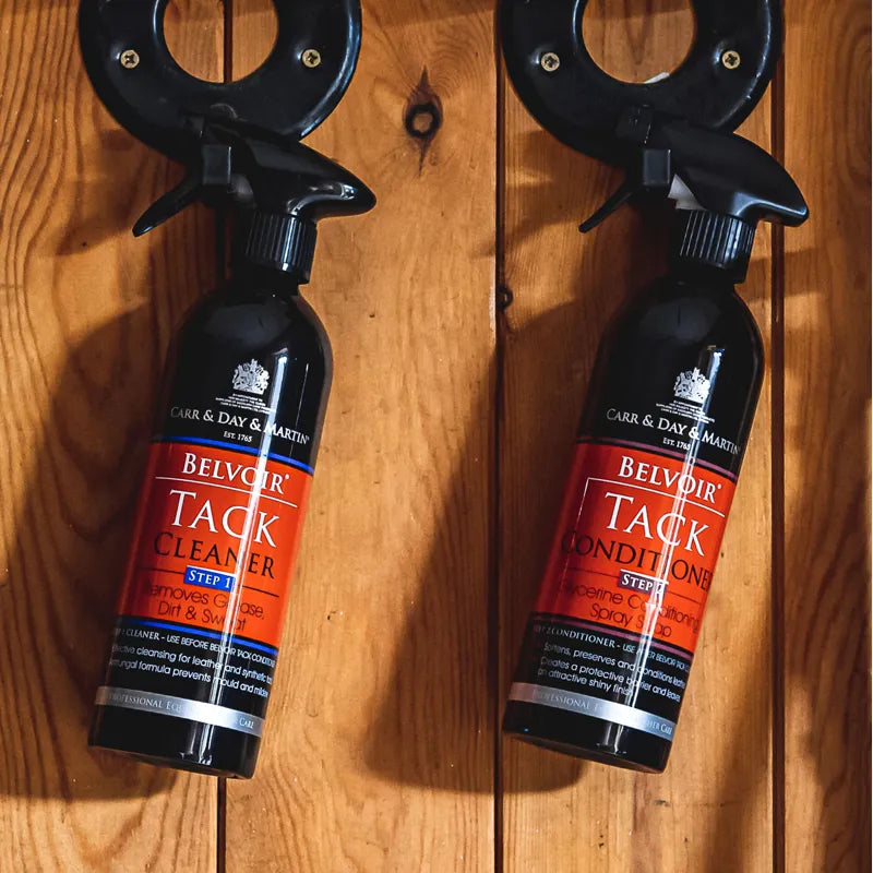Two bottles of Belvoir Tack Cleaner and Tack Condition Spray by Carr & Day & Martin, displayed side-by-side on a wooden surface with a black ring-shaped stand.