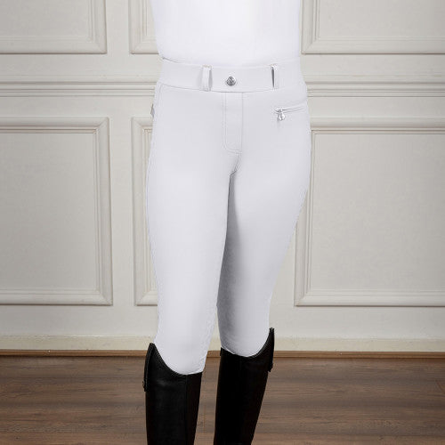White riding pants with black boots on a wooden floor and white paneled wall background