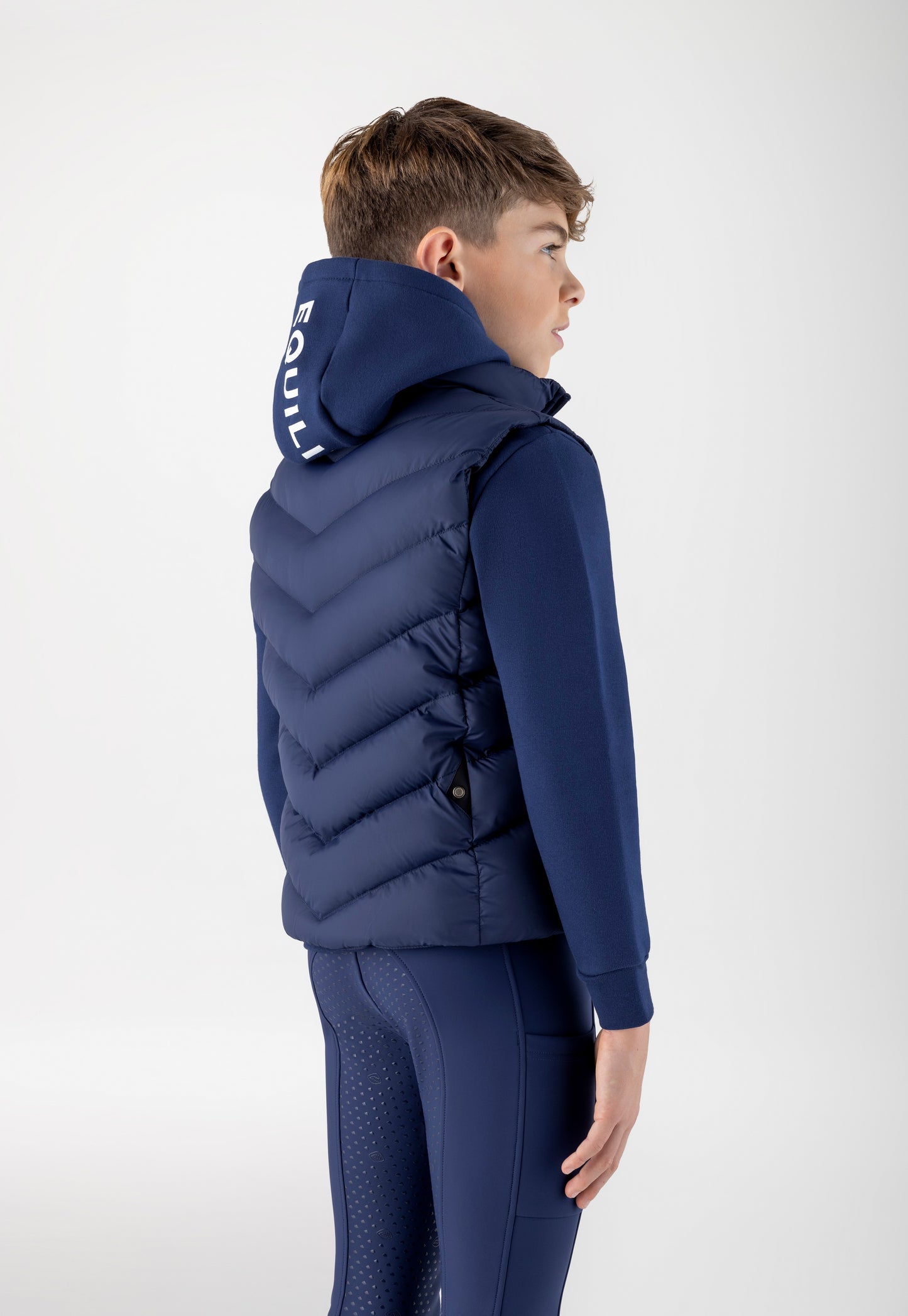 Person wearing a blue puffer vest with a visible brand logo on a white background