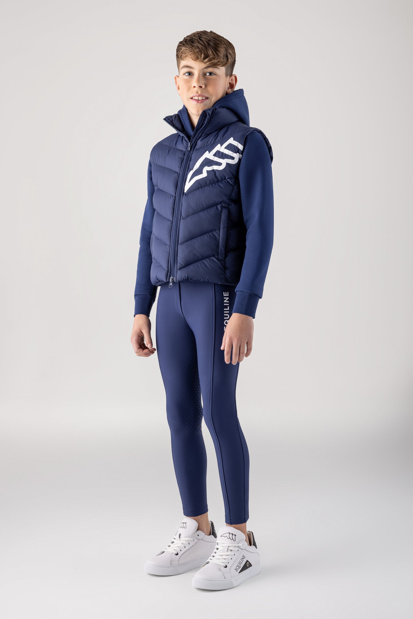 Person wearing a blue puffer jacket and pants on a white background