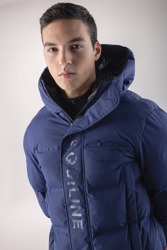 Man wearing a blue winter jacket with a brand logo on a light gray background