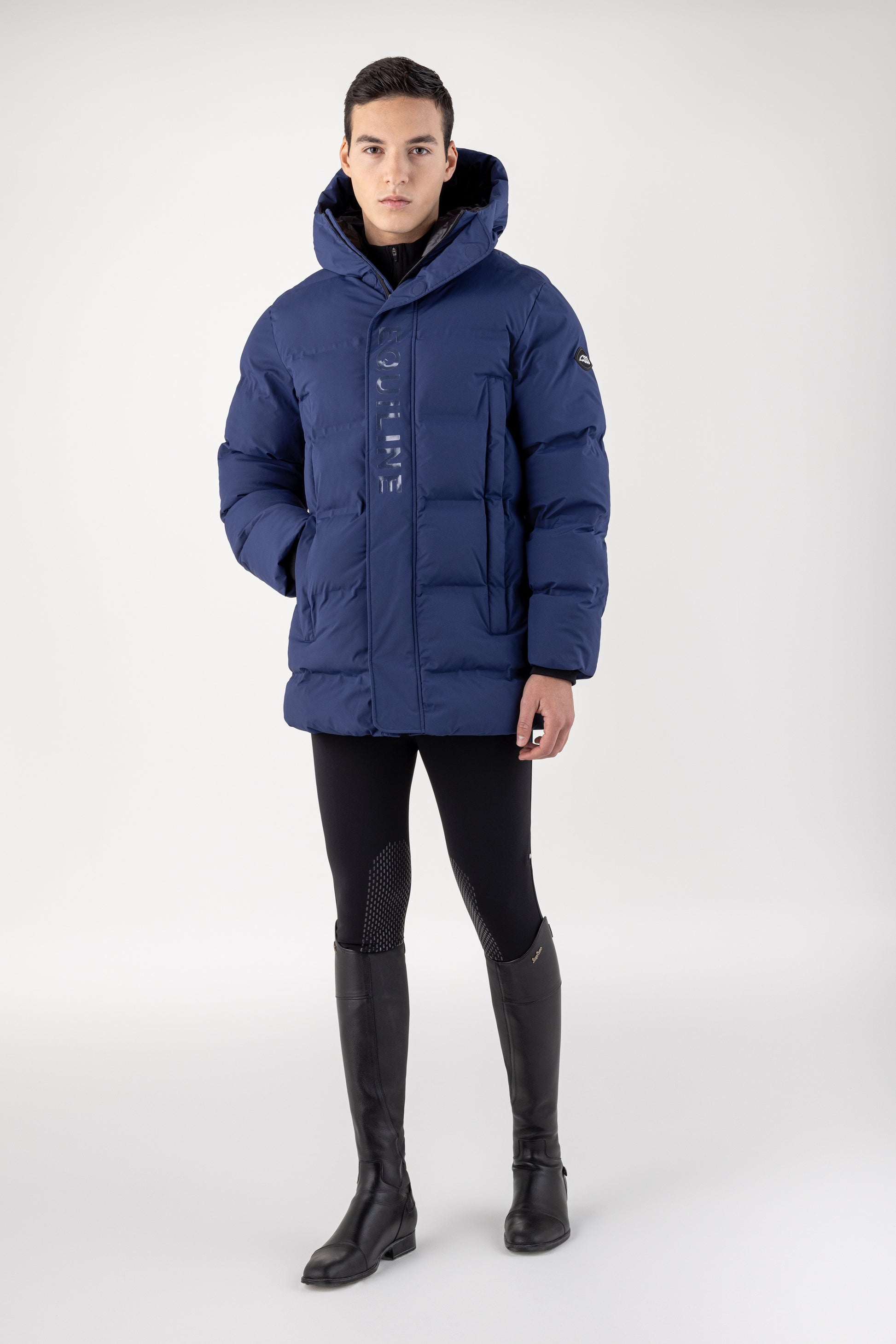 Person wearing a blue puffer jacket and black pants on a white background