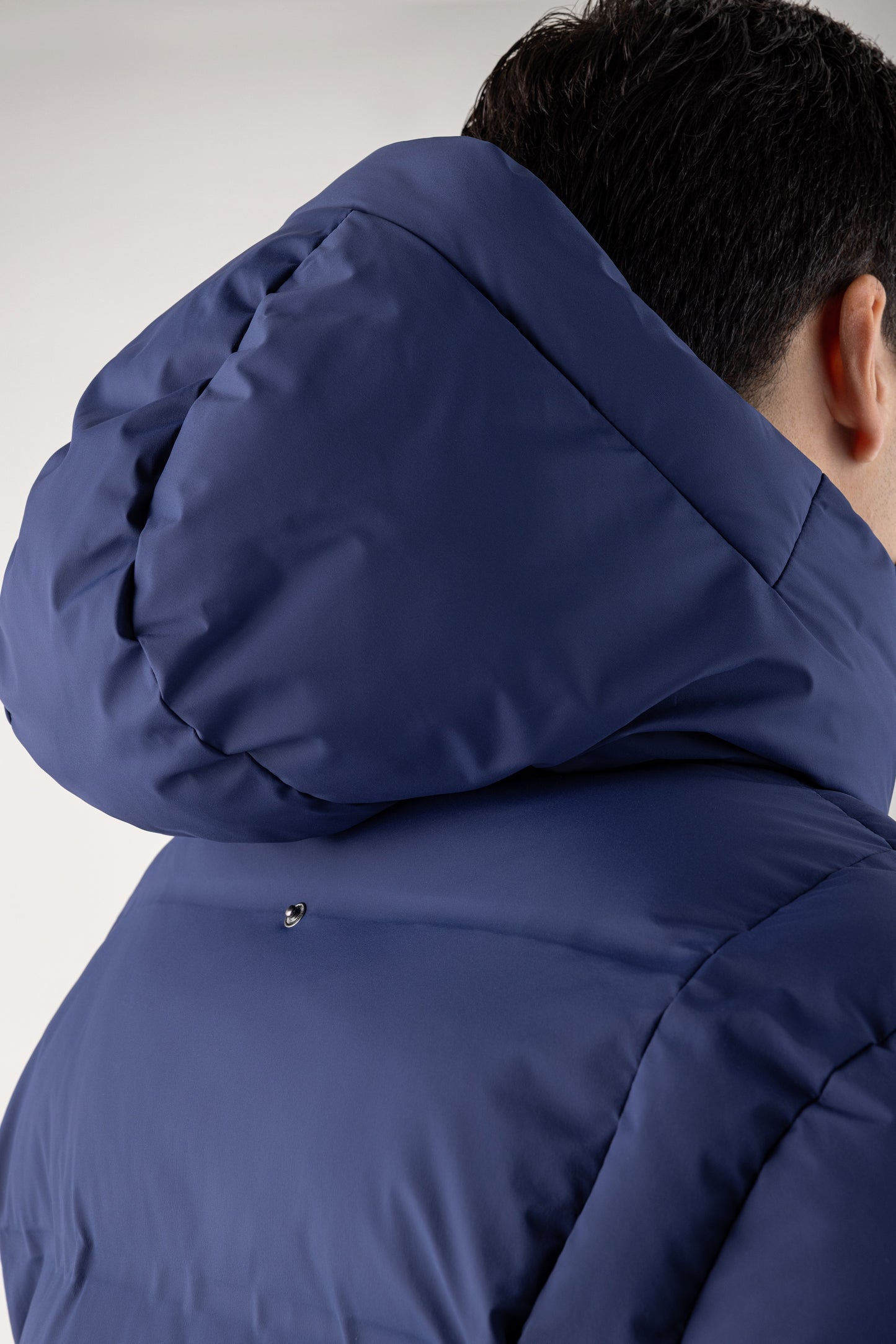 Person wearing a blue hooded jacket on a plain background