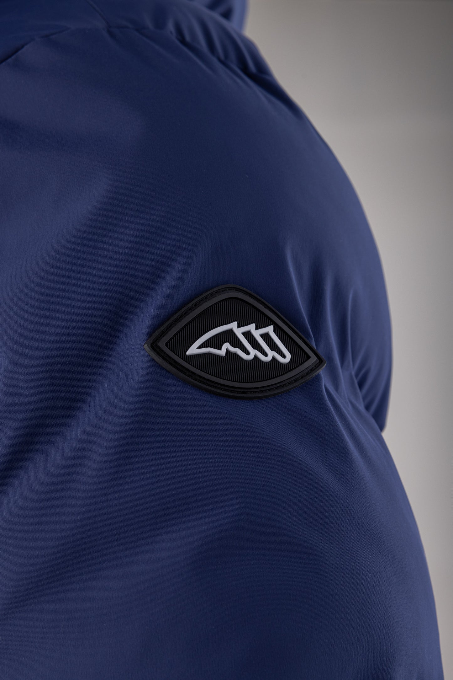Close-up of a blue jacket with a black and white logo on a gray background