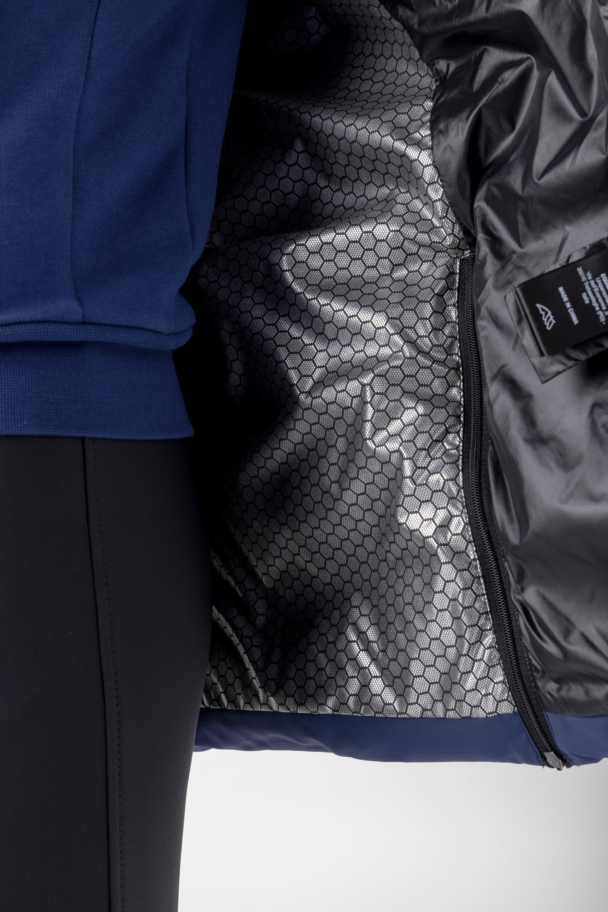 Close-up of a blue jacket with a textured black lining on a white background