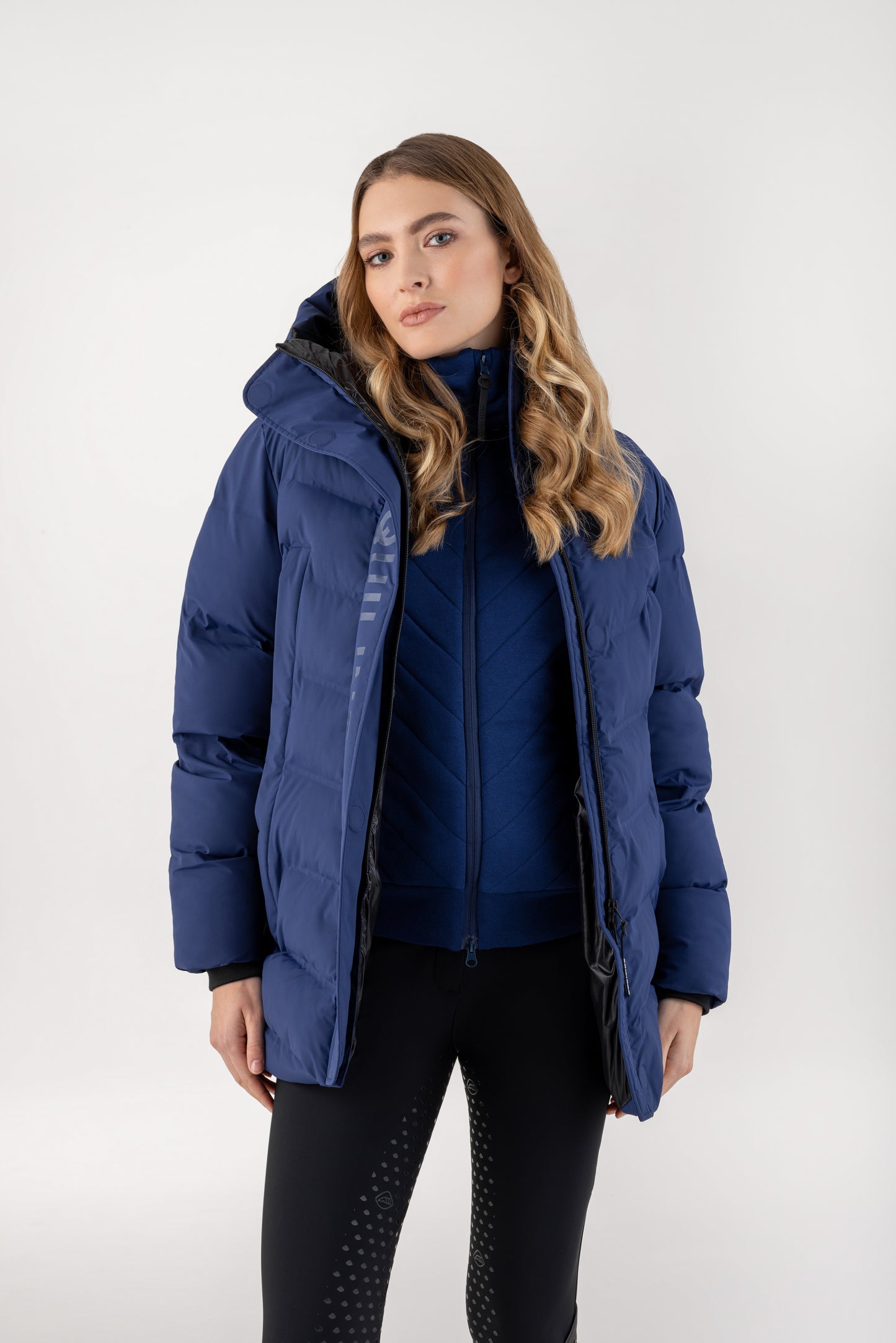 Woman wearing a blue puffer jacket on a white background