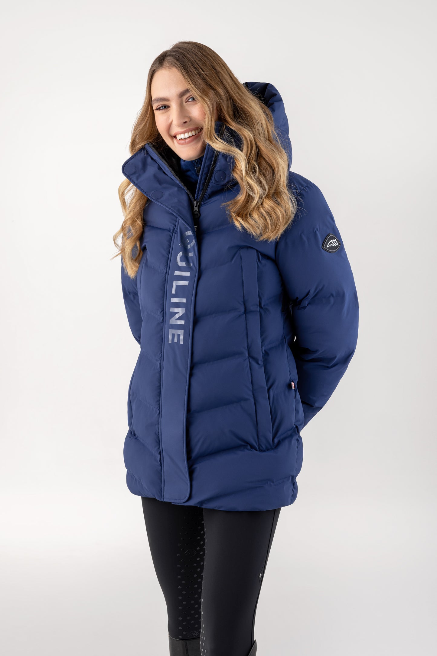 Woman wearing a blue winter jacket with a visible brand logo on a white background