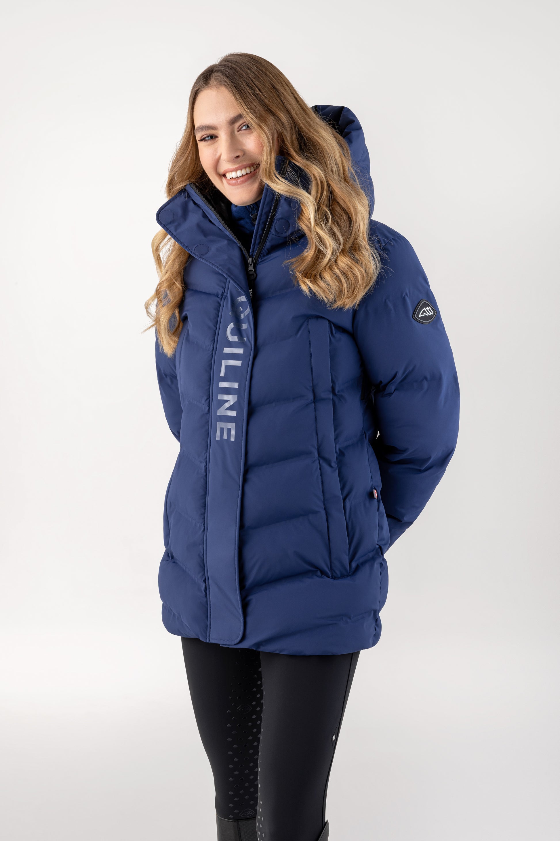 Woman wearing a blue winter jacket with a visible brand logo on a white background
