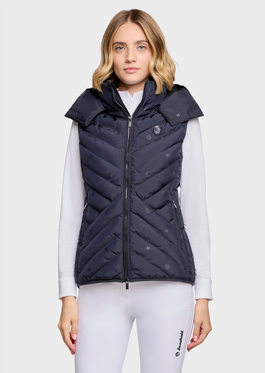 A woman modeling a sleeveless quilted puffer vest in dark navy blue. The vest features a high collar, full front zipper, and subtle tonal logo details.